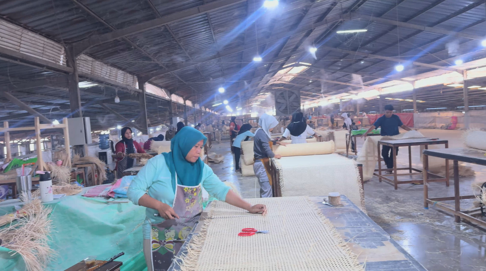 Workers weaving natural rattan panels in an Indonesia production workshop