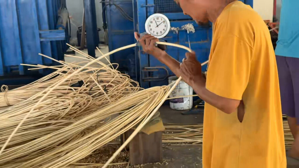 Worker checking natural rattan dimensions with a measuring tape